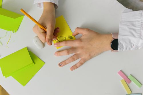 Free Capture of hands skillfully drawing with a pencil on vibrant green paper while wearing a smartwatch. Stock Photo