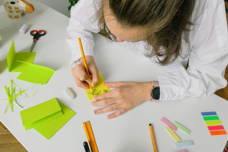 A Person In White Long Sleeves Drawing An Eye On Yellow Paper