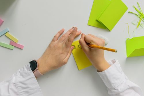 Free A person sketching on green paper with pastel sticks and eraser on a table. Stock Photo