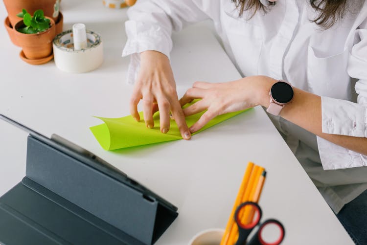 A Person In White Dress Shirt Folding A Green Paper