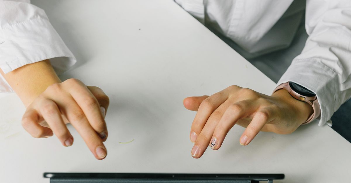 Close-up shot of a person's hand with a smartwatch, with a blurred background of a smart home dashboard on a tablet