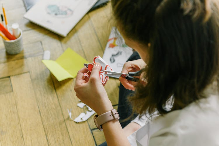 Woman In White Shirt Cutting A Paper