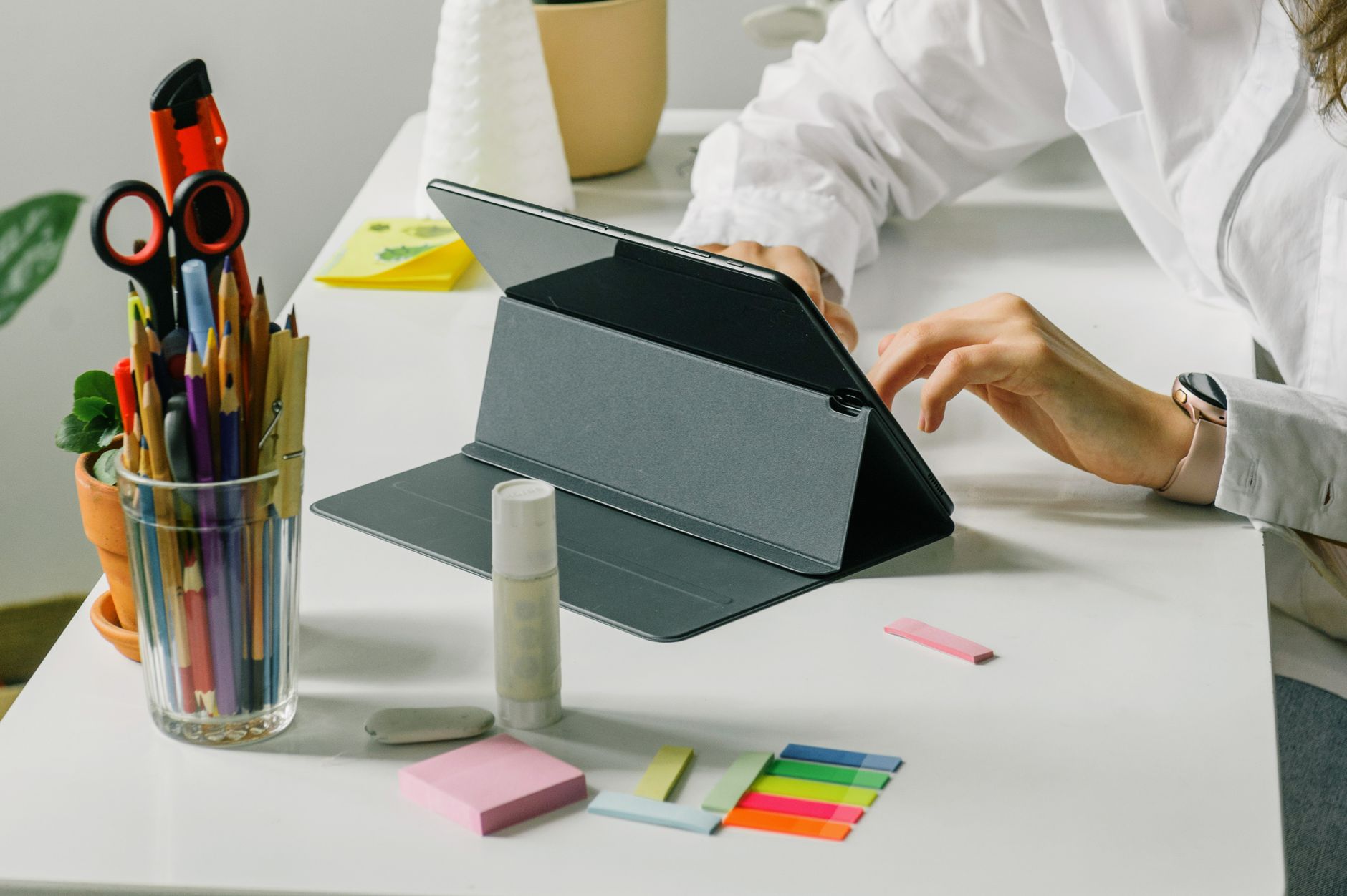 Woman using a tablet in a modern workspace with office stationery.
