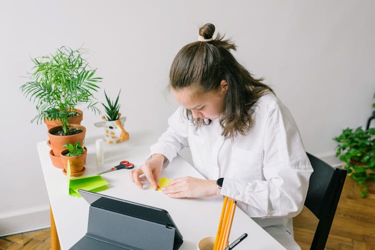 Woman In White Dress Shirt Folding A Yellow Paper