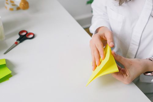 Free Person crafting with paper and scissors at a desk, showcasing creativity and art in a well-lit indoor setting. Stock Photo