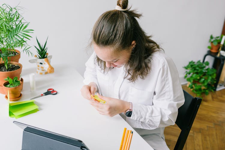 Woman In White Long Sleeve Shirt Folding A Yellow Paper