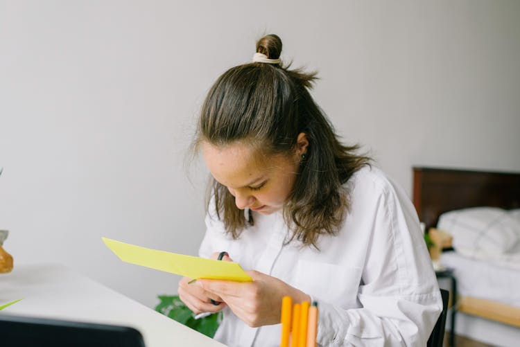 Woman In White Dress Shirt Cutting A Yellow Paper