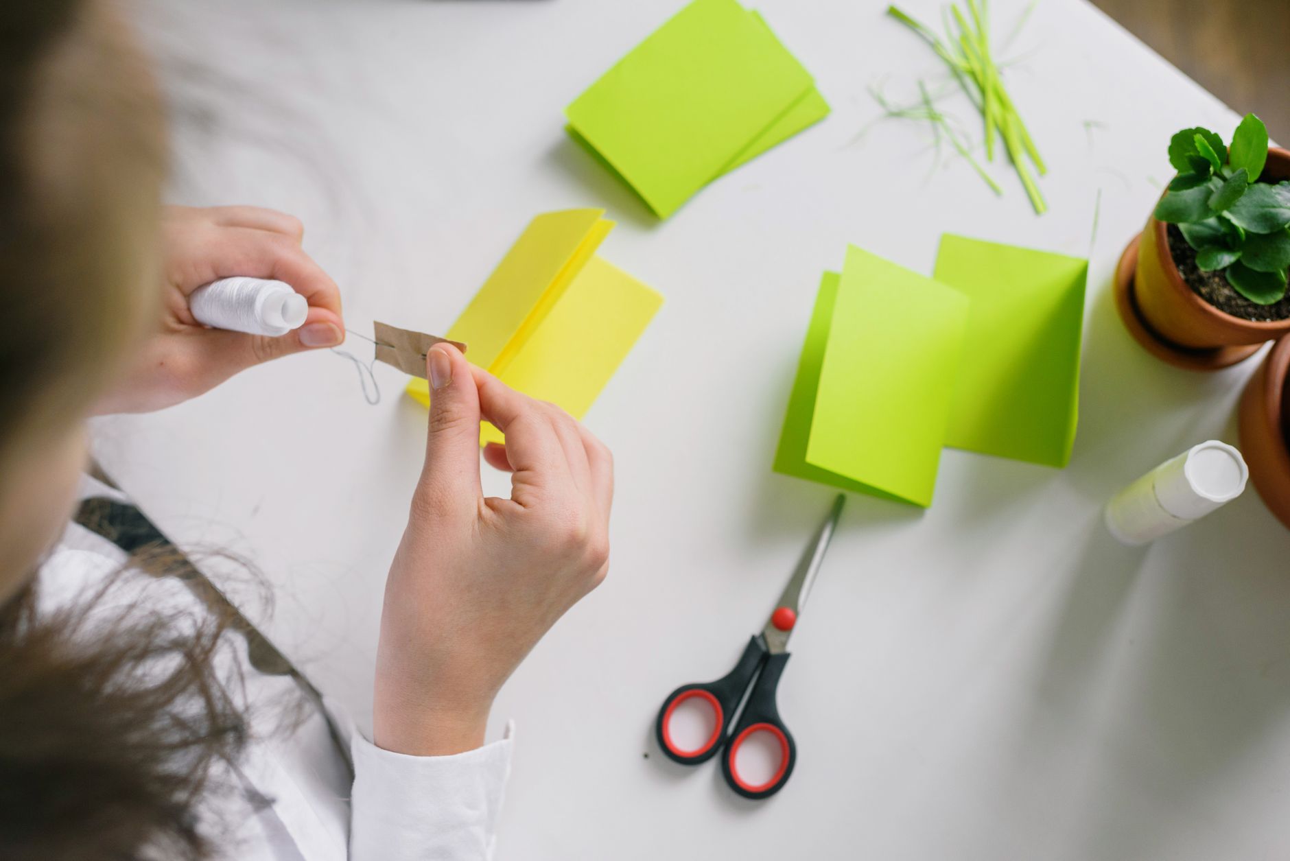 A person folding vibrant papers with tools on a desk.