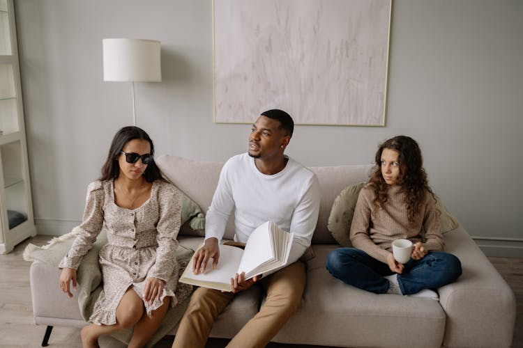 Multiracial People Sitting On Couch With Open Book