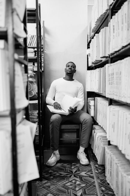 A young man reads a braille book in a library, highlighting accessibility and inclusion. A young man reads a braille book in a library, highlighting accessibility and inclusion.
