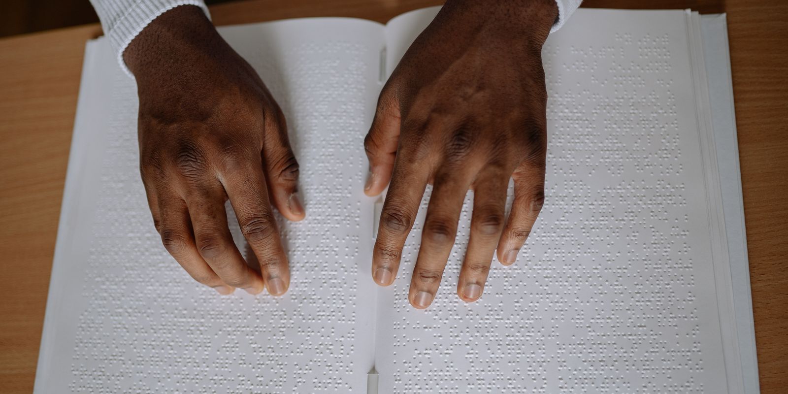 Close-up of hands reading a page of braille text