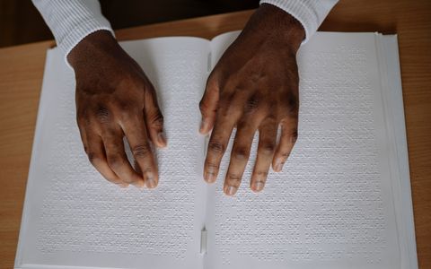 Close-up of hands reading a page of braille text
