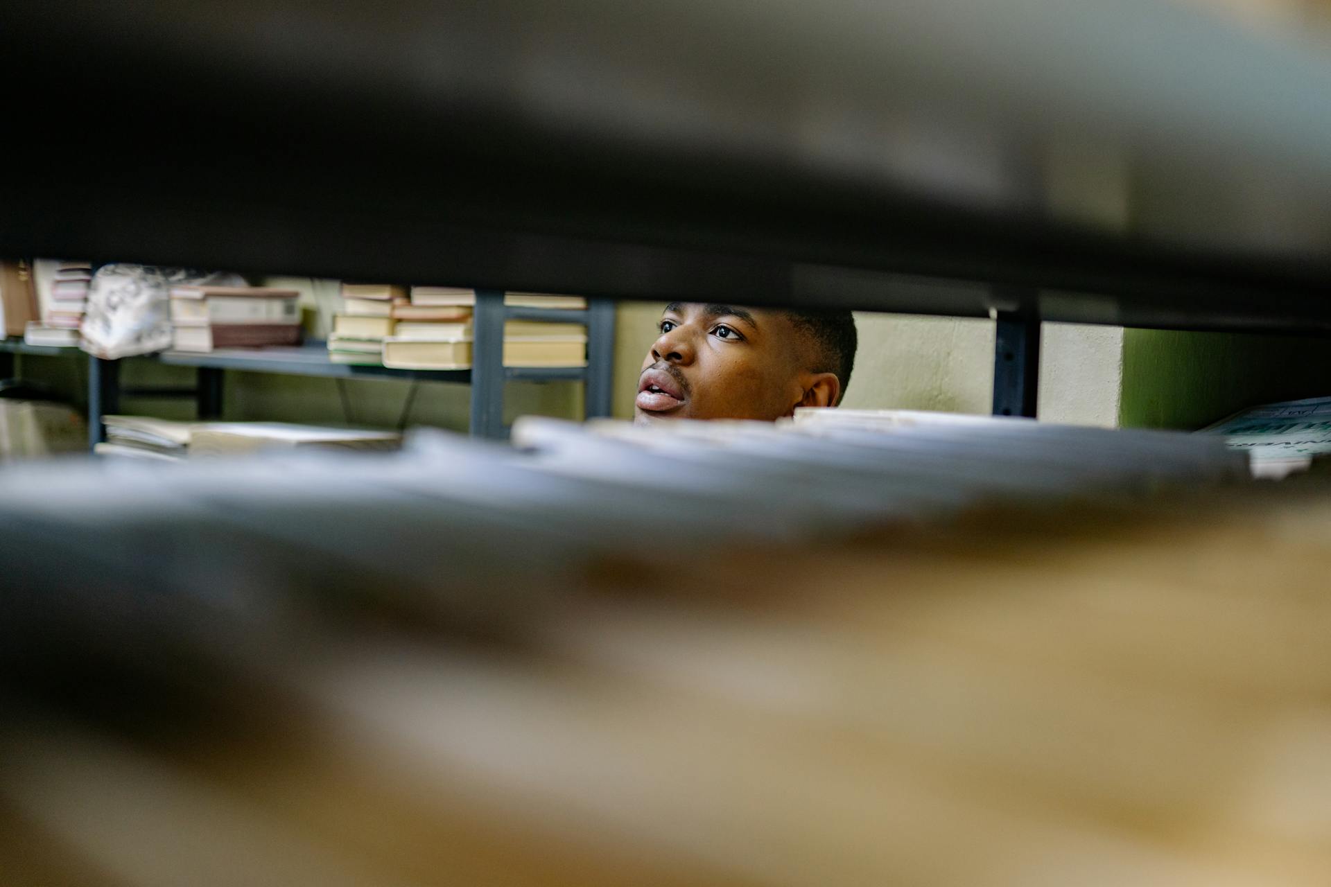 A man browsing through files in a library or archive, focused on tasks.