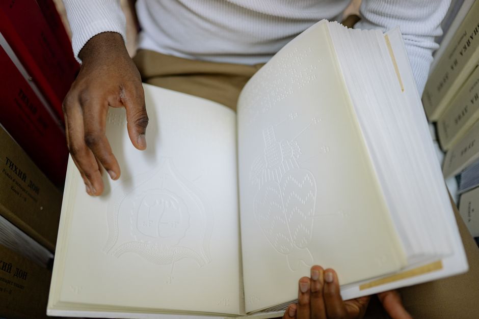 Close-up of a person reading a Braille book, highlighting accessibility for the visually impaired.