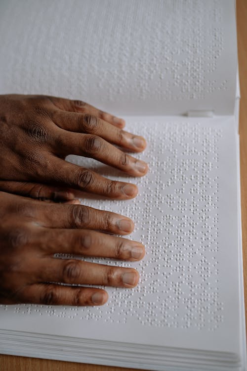 Free A Close-up Shot of a Person's Hands on White Braille Paper Stock Photo