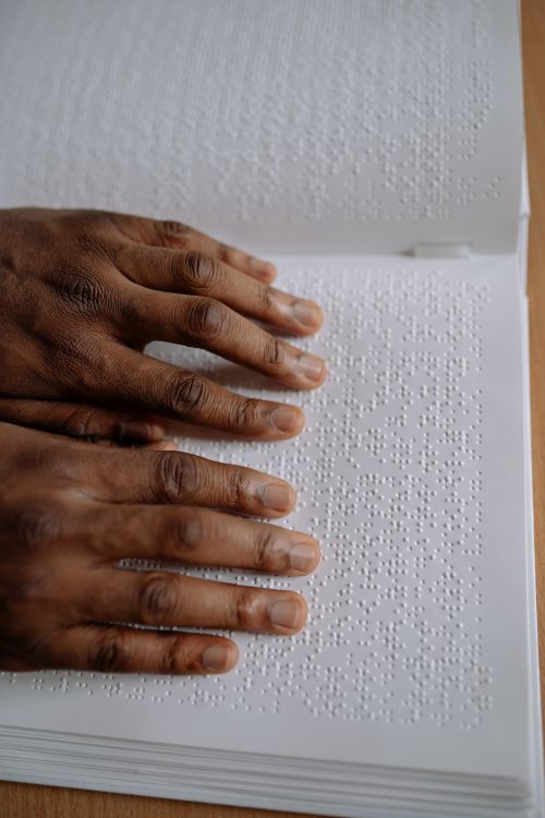 Free Close-up of hands reading a Braille book indoors. Educational and tactile reading skills for the visually impaired. Stock Photo