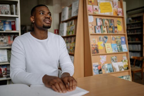 A Smiling Man Reading a Braille Book at a Library