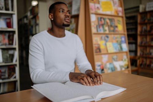 A Man Reading a Braille Book at a Library