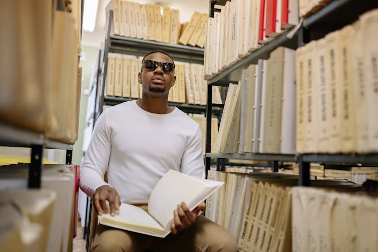 A Man In White Sweater Inside A Library