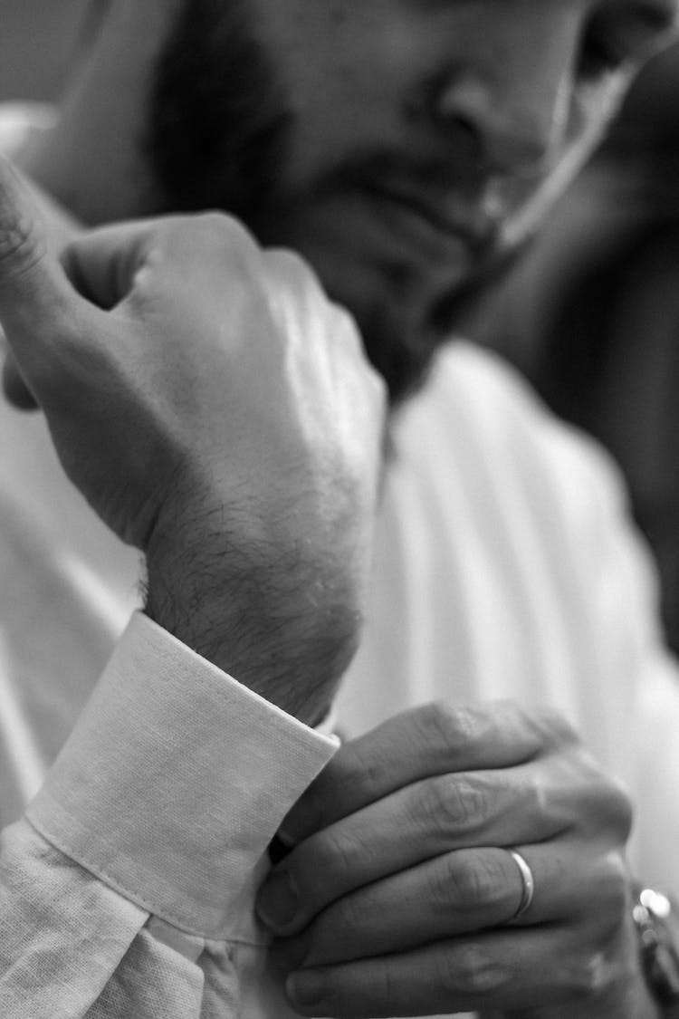 A Man Buttoning The Cuff Of His White Dress Shirt 