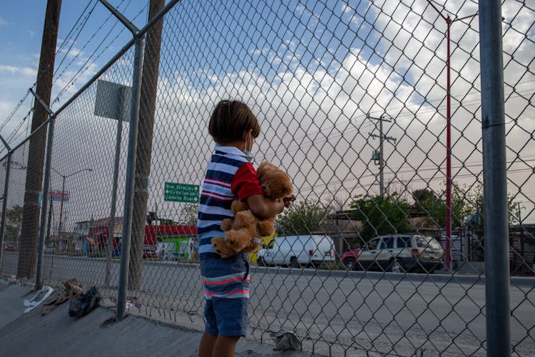 A Boy In Striped Shirt Holding A Teddy Bear