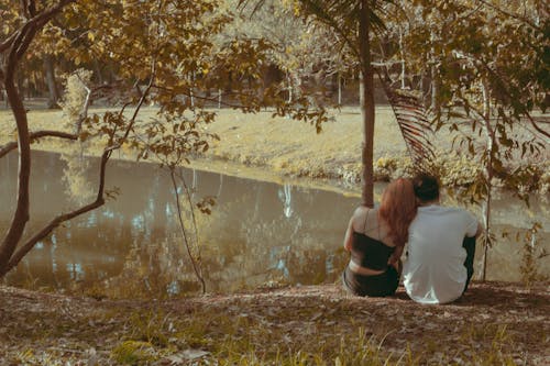 A Couple Sitting on the Side of a Lake