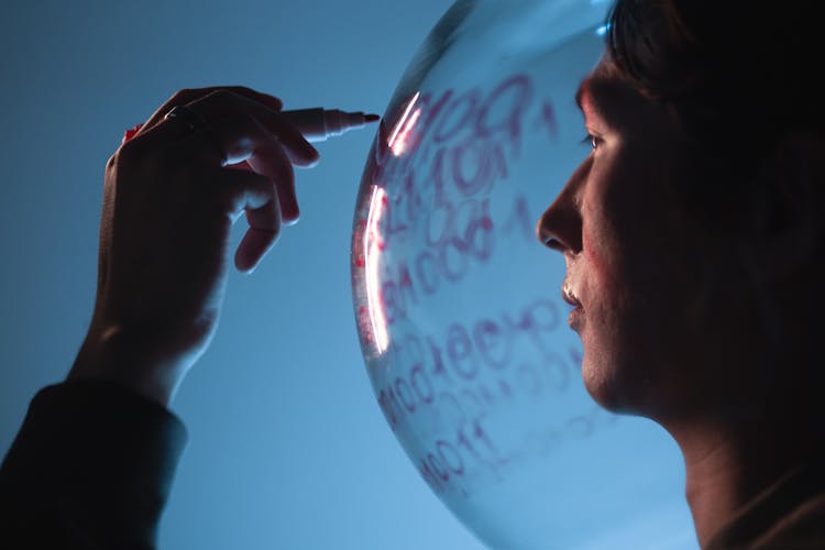 A Man Writing On A Glass Helmet With A Marker Pen