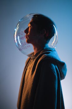 Artistic profile of a man in a hoodie wearing a glass sphere helmet in studio lighting.