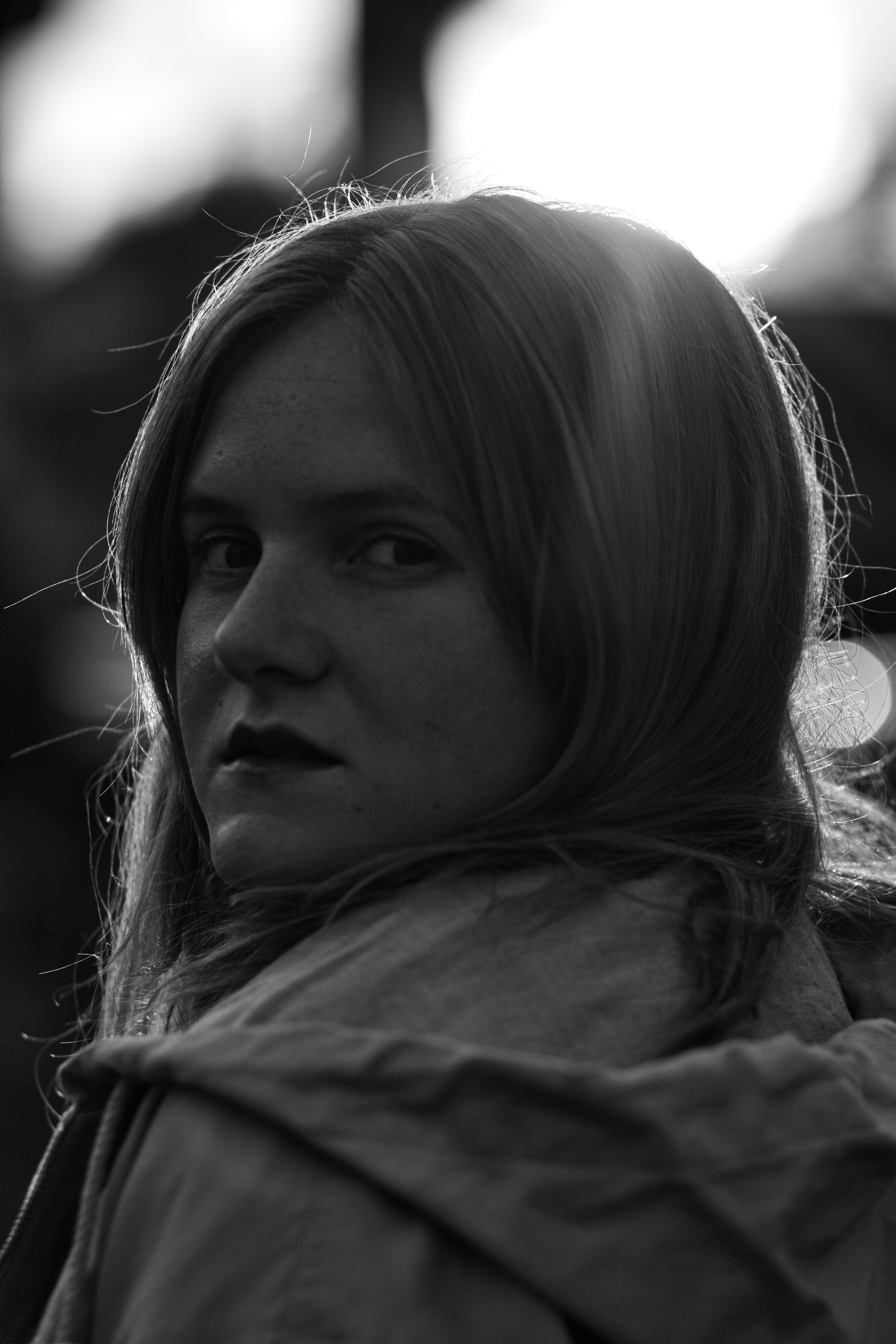 A woman looking back in a dramatic black and white outdoor portrait.