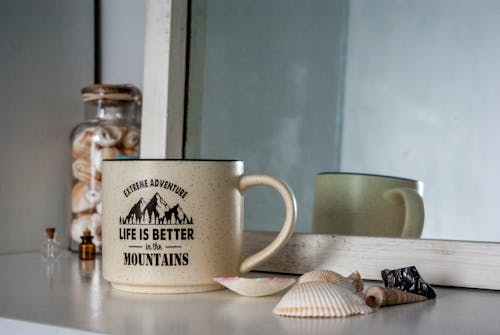Free Mug with inscription Life is better in the mountains placed near seashells Stock Photo