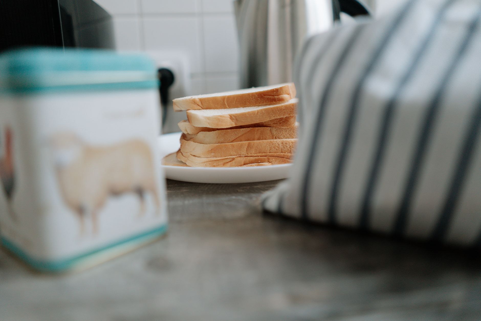 Close-up of sliced bread on a ceramic plate beside a striped cloth. Perfect for cozy kitchen or breakfast themes.