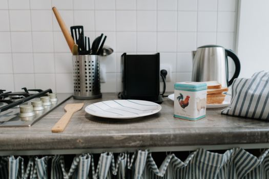 A clean kitchen counter featuring utensils, a kettle, and a tin can with vibrant design.
