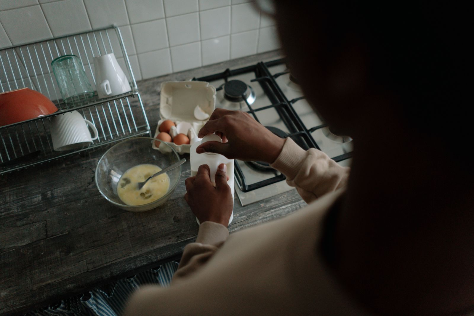 Unrecognizable person preparing breakfast with eggs and milk in a home kitchen.