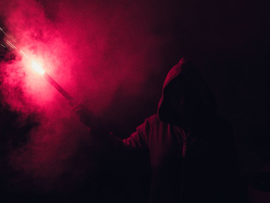 Hooded Figure Holding Red Flare · Free Stock Photo