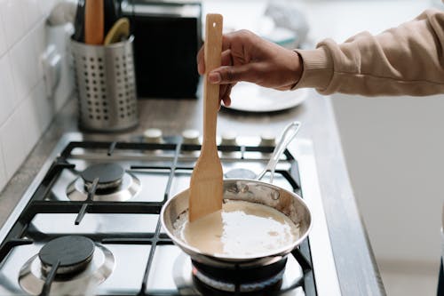 Free Person Holding Brown Wooden Ladle on a Pan Stock Photo