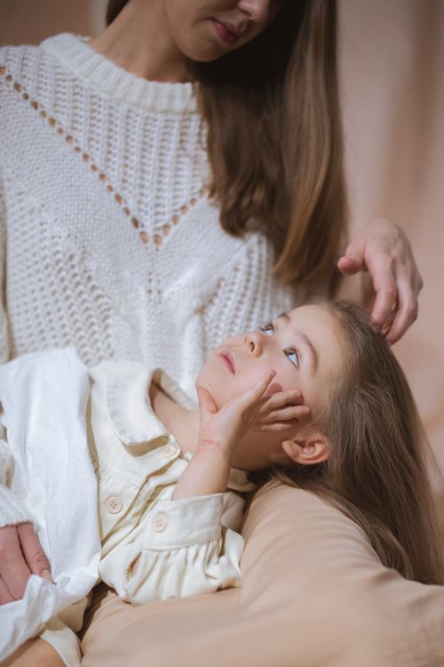 Free A loving mother gently strokes her child's hair while they share a serene moment indoors. Stock Photo