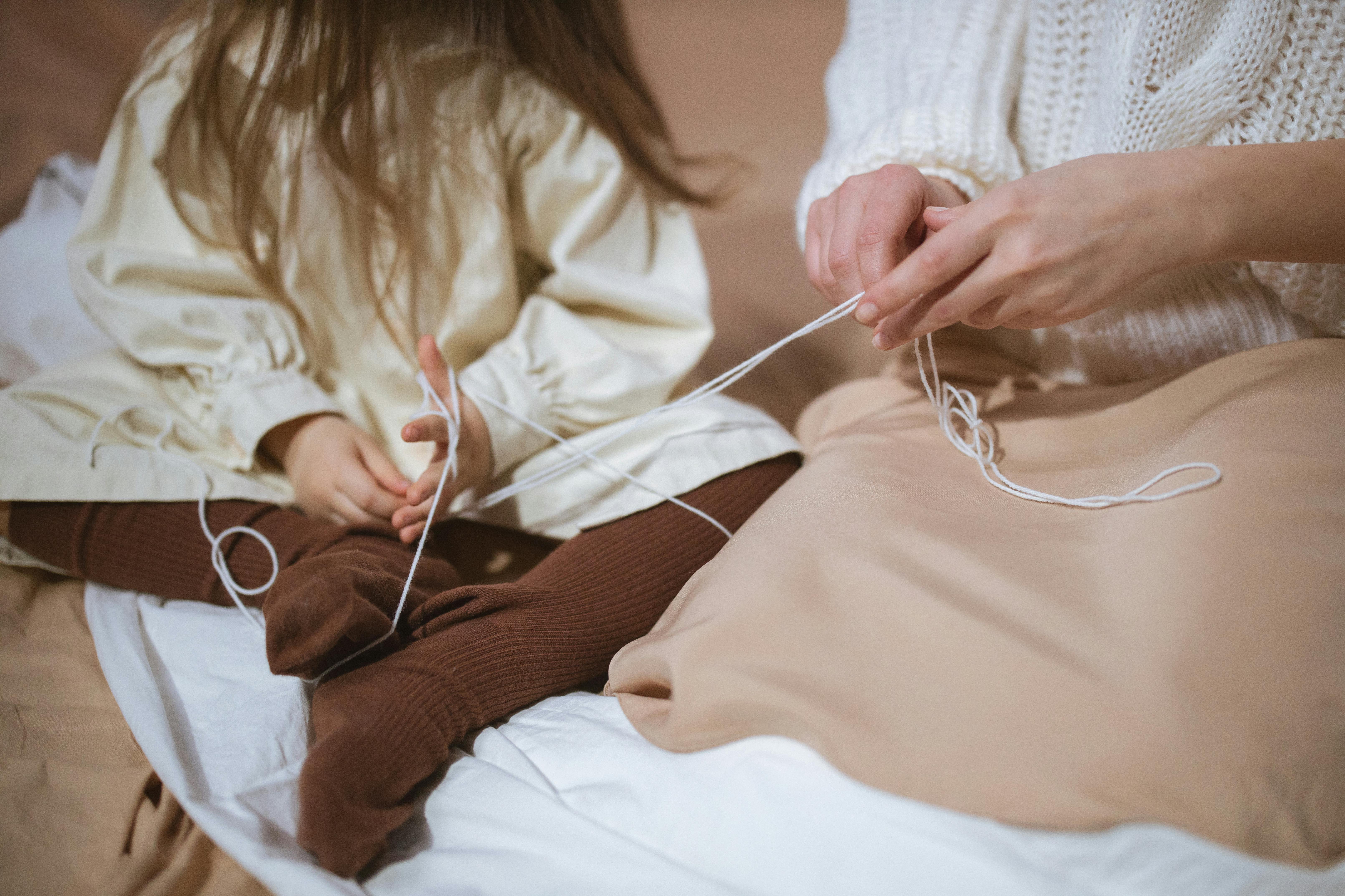 a mother and daughter holding a white thread