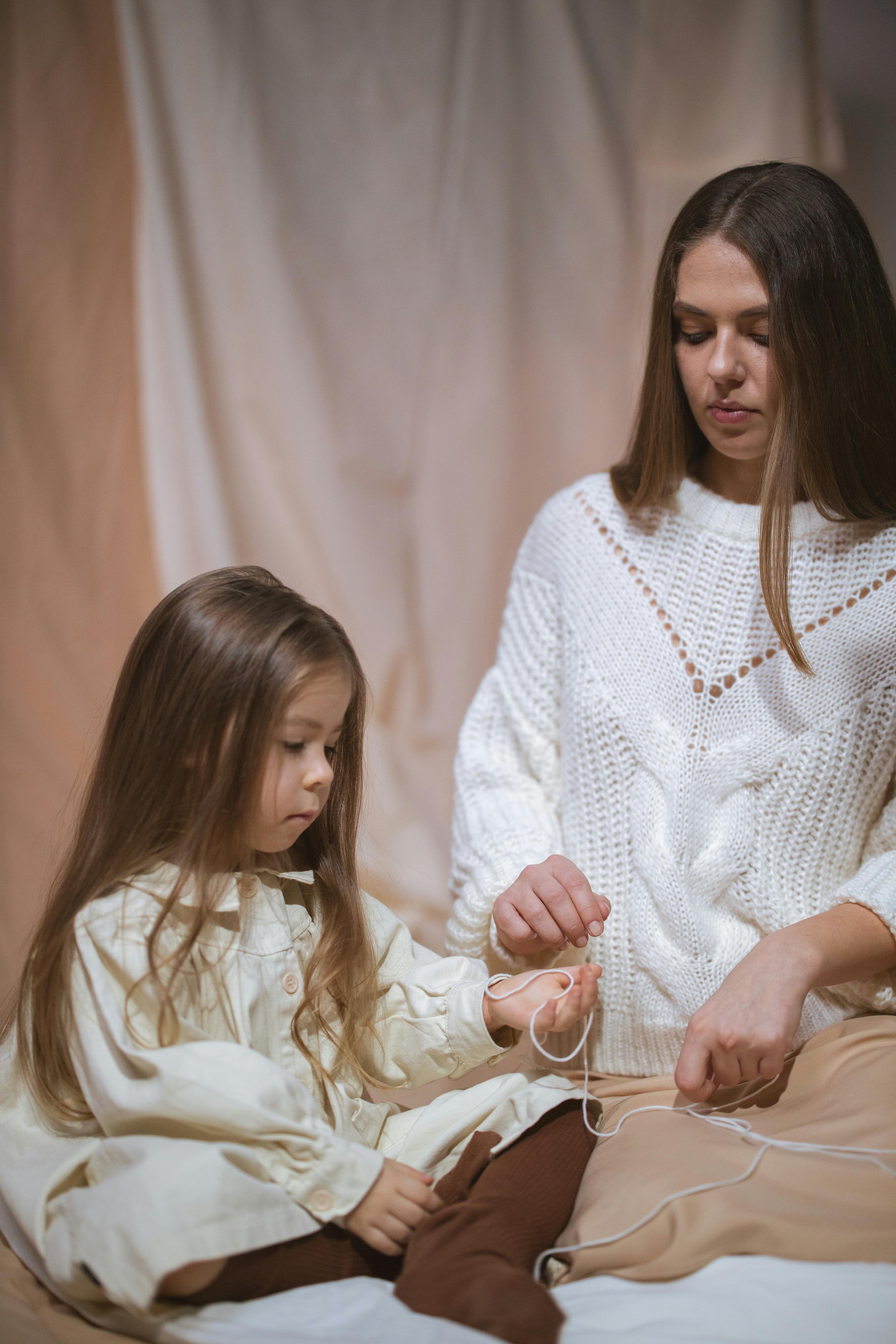 mother and daughter with yarn thread sitting in studio