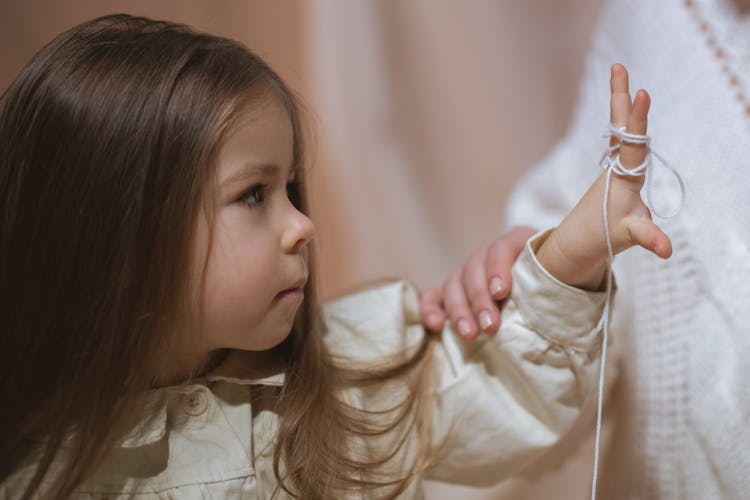 Little Girl Playing With Thread