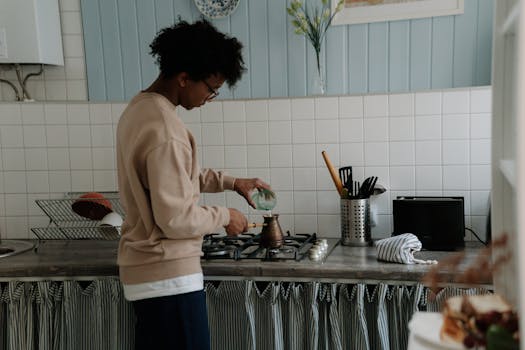 A young man making coffee on a gas stove in a cozy kitchen setting.
