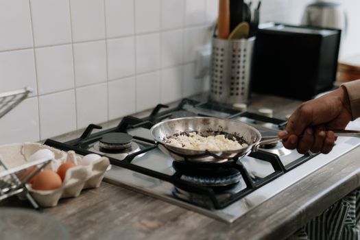 A close-up of scrambled eggs being prepared on a gas stove indoors. Perfect for culinary themes.