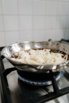 Close-up of scrambled eggs cooking in a stainless steel pan on a gas stove.