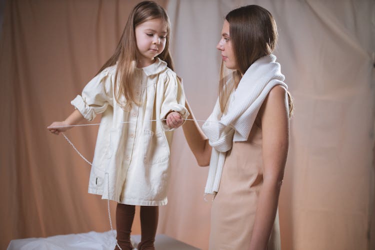 A Child Pulling Thread From The Scarf Of A Woman