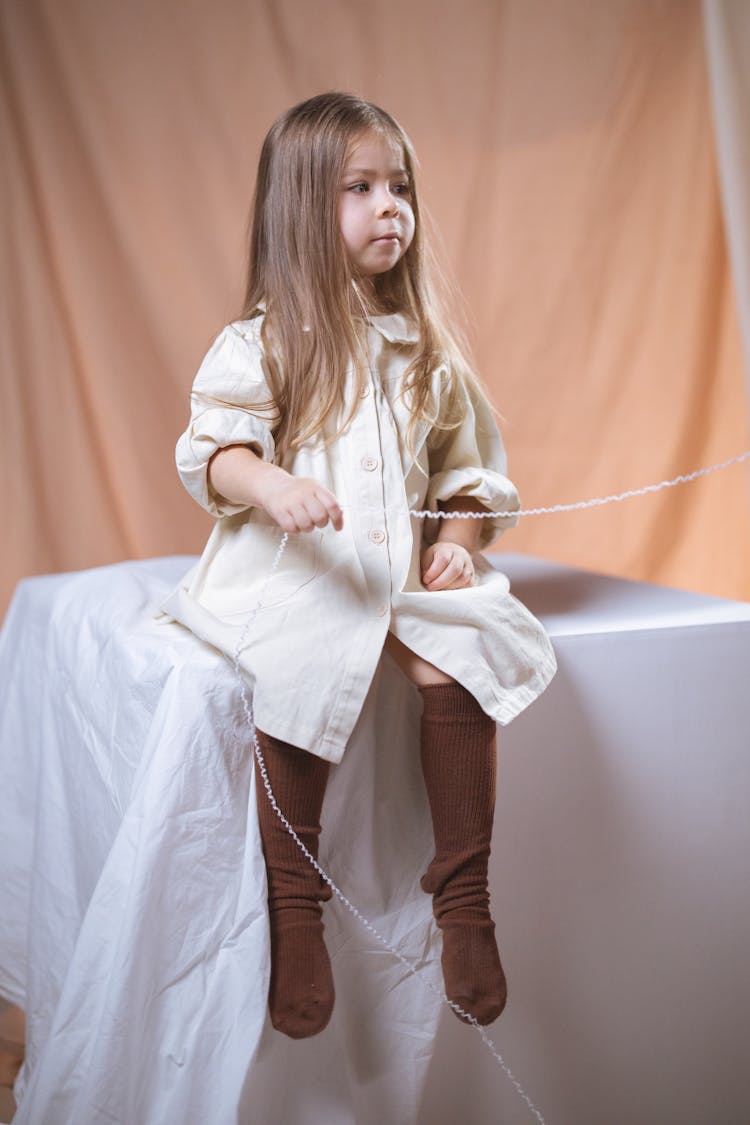 Little Girl Sitting On Cube In Studio