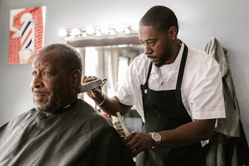 Barber Making Haircut for Mature Black Man in Barbershop