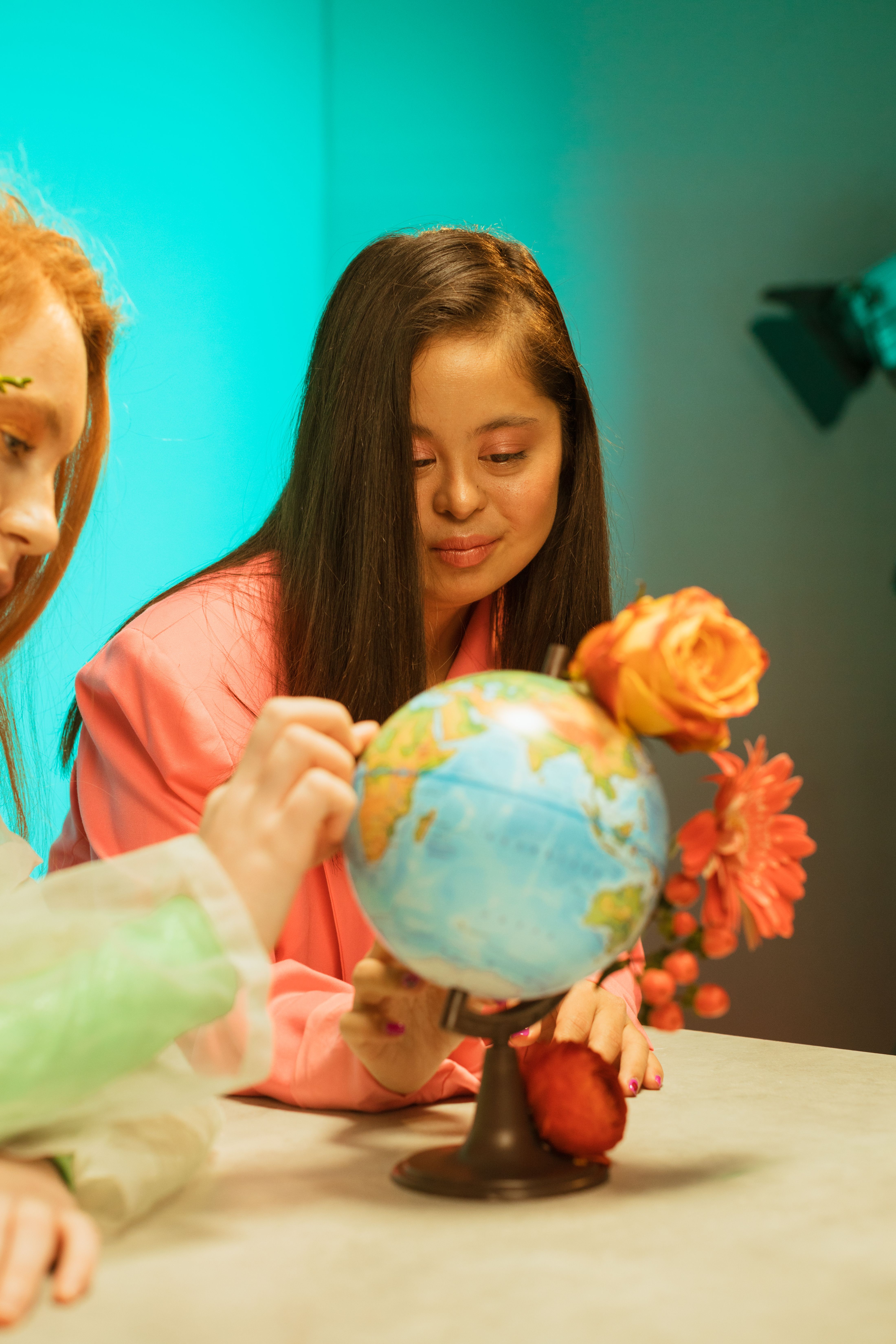 Young woman interacting with a globe adorned with flowers, highlighting diversity and education.