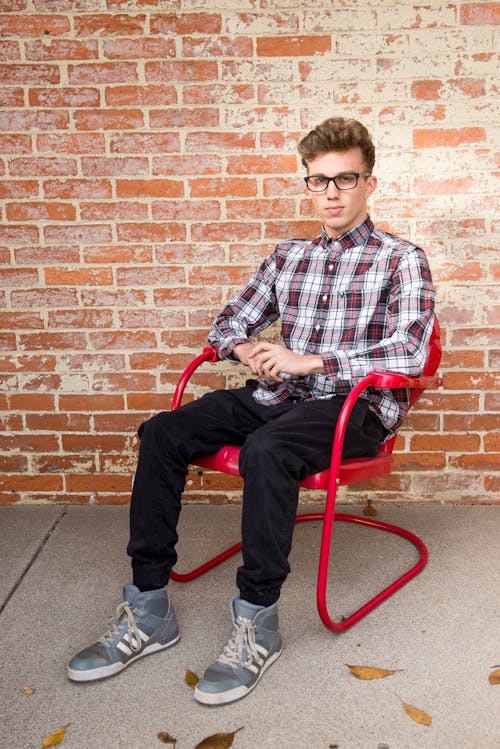 Free Man Wearing White And Red Long Sleeve Shirt Sitting On Red Steel Armchair Stock Photo