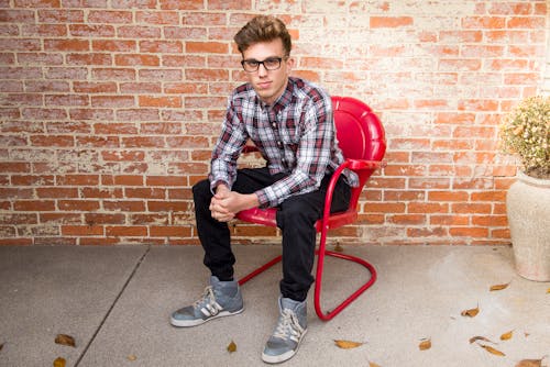 Man In Plaid Long-Sleeved Shirt And Black Pants Sitting On Red Chair