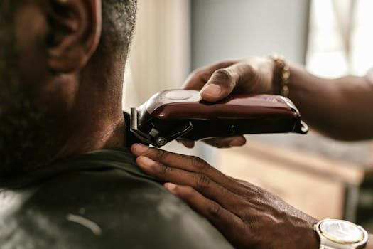 Barber using clippers to trim a client's hair in a barbershop setting.