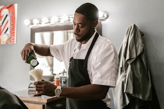 A barber in an apron prepares a brush inside an indoor barber shop, focusing on grooming tools.